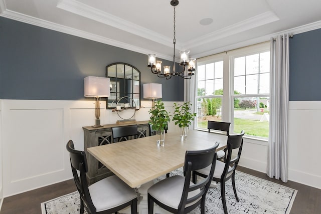 dining area with a chandelier, a tray ceiling, crown molding, and dark wood-type flooring