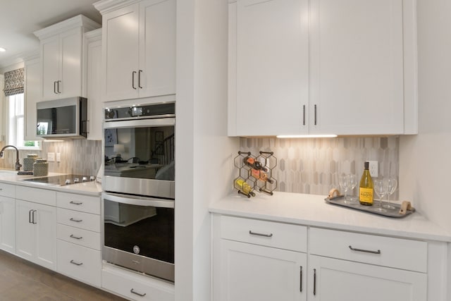 kitchen featuring white cabinets, decorative backsplash, and stainless steel appliances