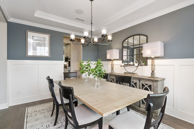 dining space featuring a raised ceiling, dark hardwood / wood-style flooring, a notable chandelier, and ornamental molding