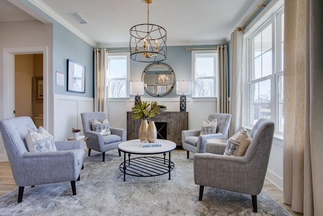 living area with a wealth of natural light, light hardwood / wood-style floors, and ornamental molding