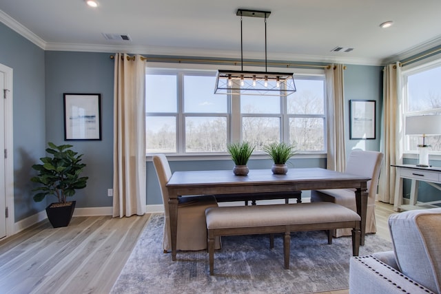 dining space featuring light hardwood / wood-style floors, crown molding, and an inviting chandelier