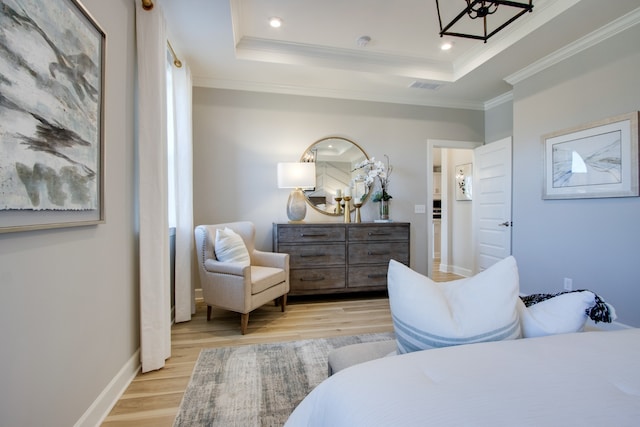 bedroom featuring a tray ceiling, ornamental molding, and light wood-type flooring