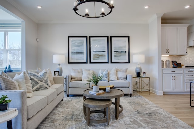 living room with a chandelier, light wood-type flooring, and crown molding