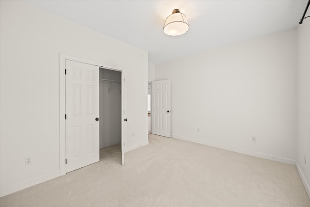 unfurnished bedroom with light carpet and a closet