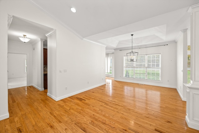 unfurnished living room featuring ornate columns, a notable chandelier, crown molding, a tray ceiling, and light wood-type flooring