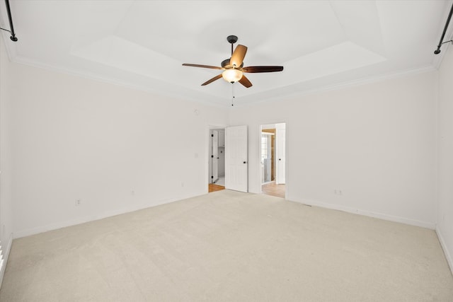 unfurnished room with light carpet, crown molding, and a tray ceiling