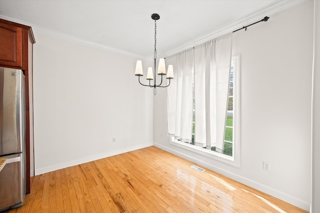 unfurnished dining area with wood-type flooring, crown molding, and an inviting chandelier