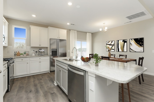 kitchen featuring pendant lighting, a kitchen island with sink, sink, white cabinetry, and stainless steel appliances