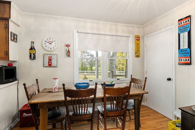 dining space with crown molding and light hardwood / wood-style flooring