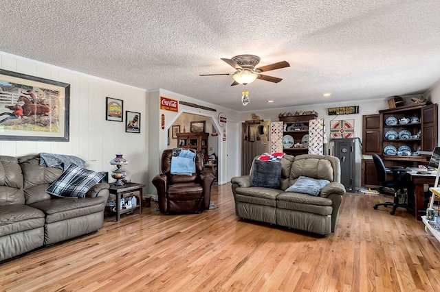 living room with light hardwood / wood-style floors, ceiling fan, a textured ceiling, and ornamental molding