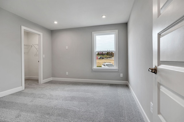 unfurnished bedroom featuring light carpet, a spacious closet, and a closet