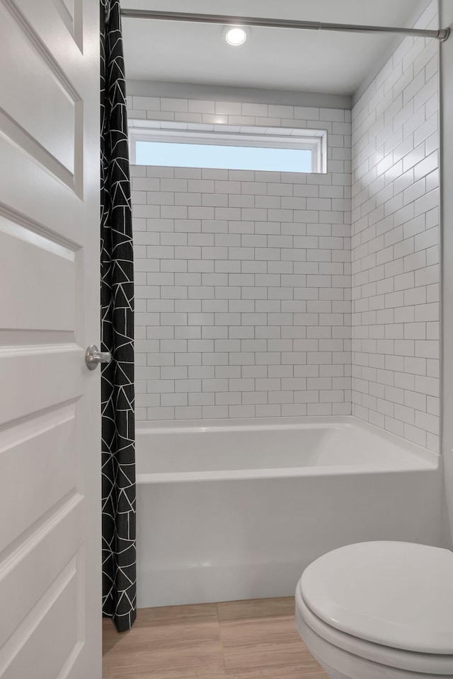 bathroom with shower / bath combo, hardwood / wood-style flooring, and toilet