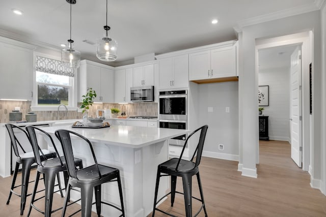 kitchen featuring stainless steel appliances, white cabinetry, a kitchen island, and light hardwood / wood-style flooring