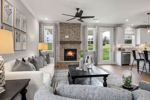 living room featuring a fireplace, hardwood / wood-style floors, ceiling fan, and ornamental molding