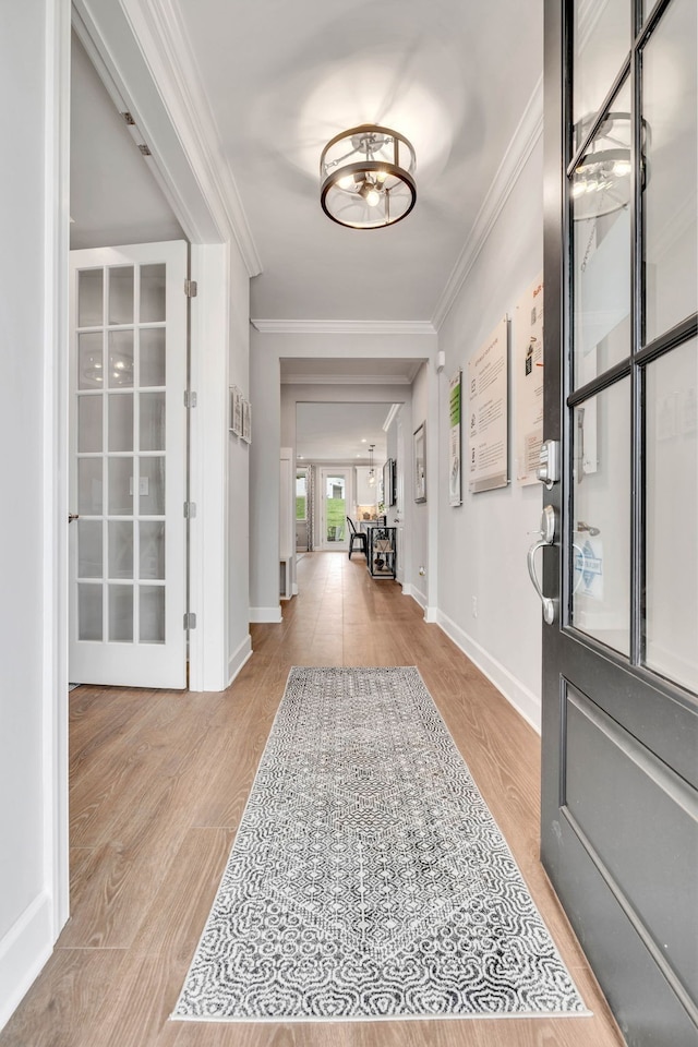 entryway with light wood-type flooring and crown molding