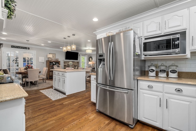 kitchen with stainless steel appliances, hardwood / wood-style flooring, white cabinetry, decorative light fixtures, and decorative backsplash