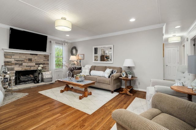 living room with a stone fireplace, light wood-type flooring, and crown molding