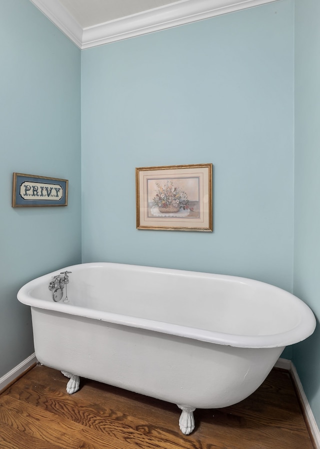 bathroom with wood-type flooring, a washtub, and crown molding