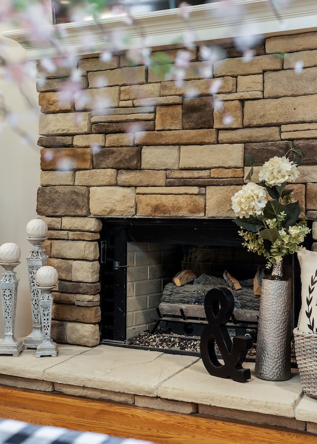 details featuring a stone fireplace, hardwood / wood-style flooring, and ornamental molding