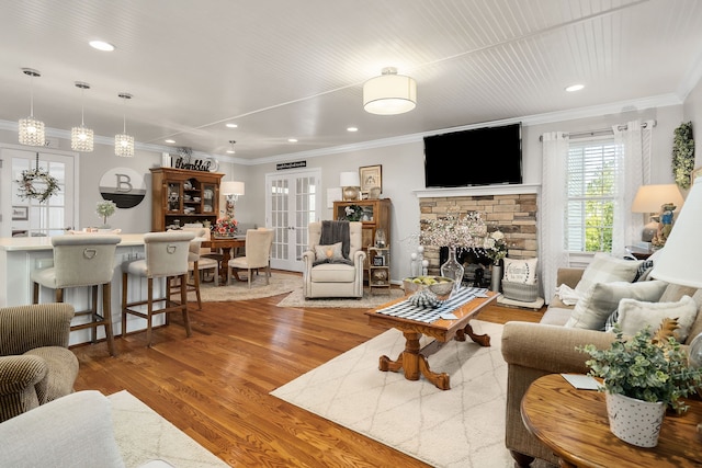 living room featuring hardwood / wood-style floors, a fireplace, french doors, and ornamental molding