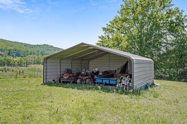 view of outdoor structure with a carport, a lawn, and a mountain view