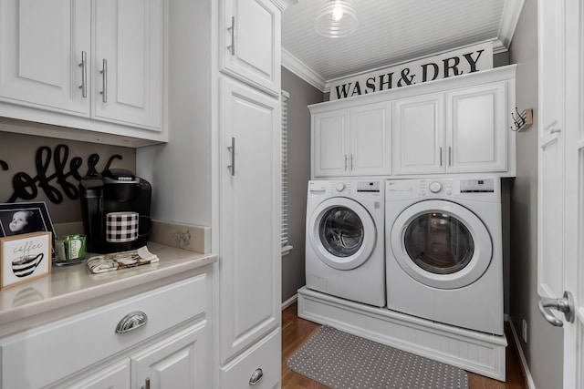 laundry area featuring ornamental molding, dark wood-type flooring, washer and clothes dryer, and cabinets