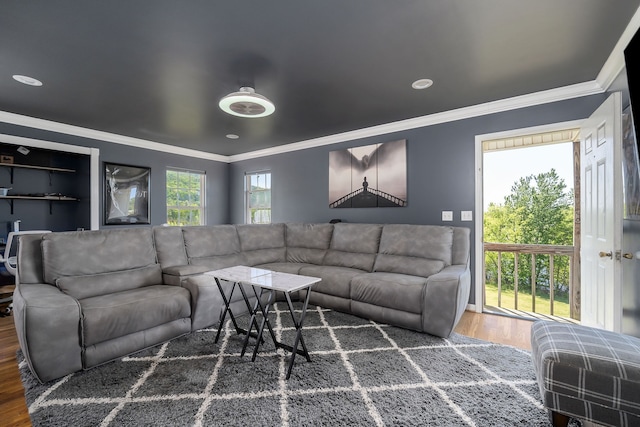 living room with dark wood-type flooring, a healthy amount of sunlight, and crown molding