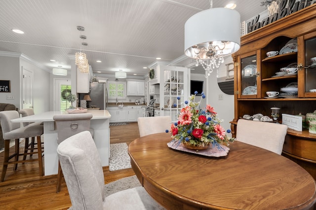 dining room featuring a notable chandelier, light hardwood / wood-style floors, and crown molding