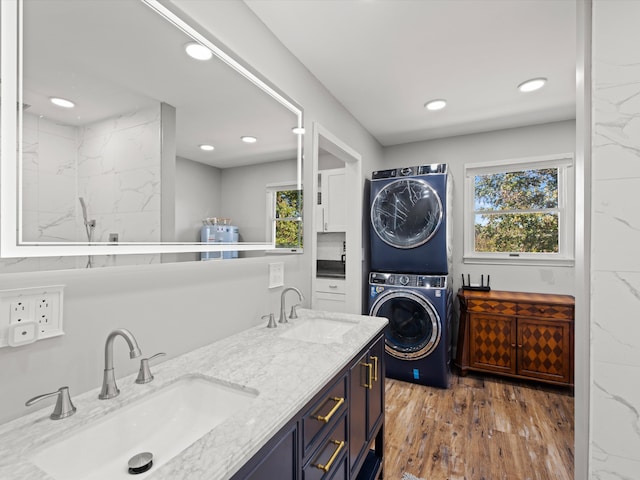 clothes washing area featuring stacked washer and dryer, wood-type flooring, and sink