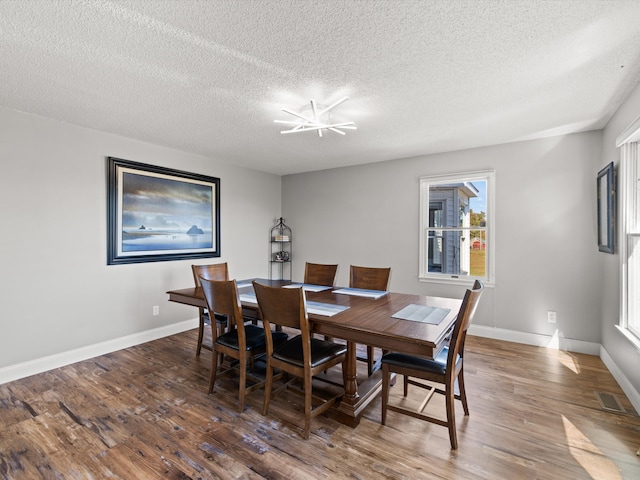 dining space with dark wood-type flooring, a chandelier, and a textured ceiling