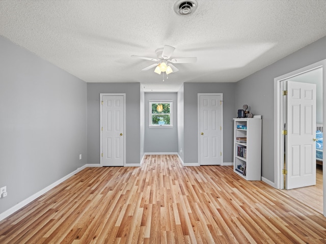 interior space featuring ceiling fan, a textured ceiling, and light hardwood / wood-style flooring