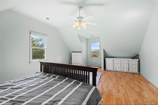 bedroom featuring light wood-type flooring, lofted ceiling, multiple windows, and ceiling fan