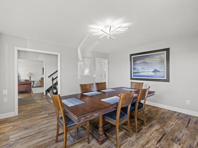 dining space featuring an inviting chandelier, wood-type flooring, and a textured ceiling