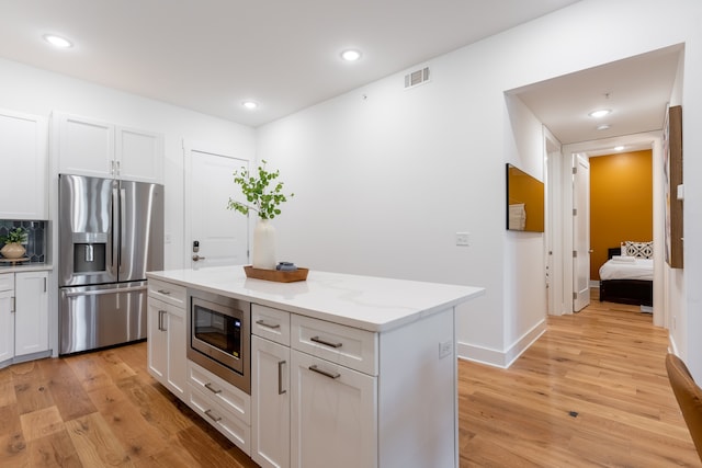 kitchen featuring stainless steel appliances, light hardwood / wood-style floors, white cabinetry, and a center island