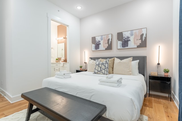 bedroom with light wood-type flooring and ensuite bath