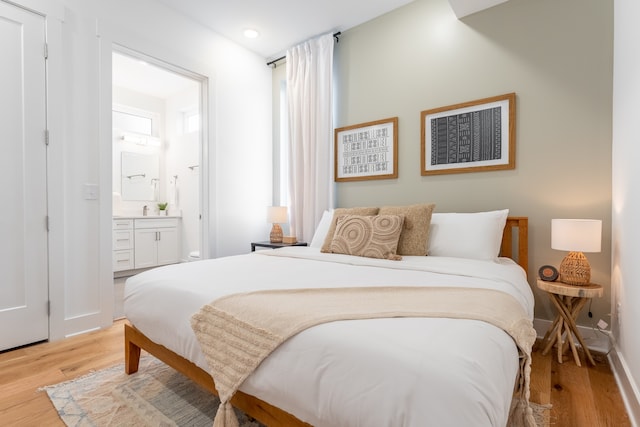 bedroom with ensuite bath and light wood-type flooring