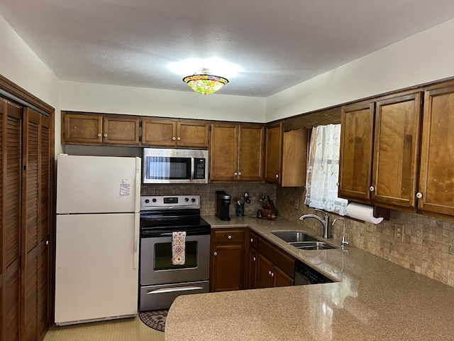 kitchen featuring tasteful backsplash, appliances with stainless steel finishes, a textured ceiling, sink, and kitchen peninsula