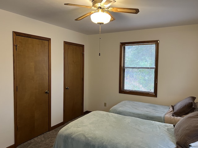 carpeted bedroom featuring multiple closets and ceiling fan