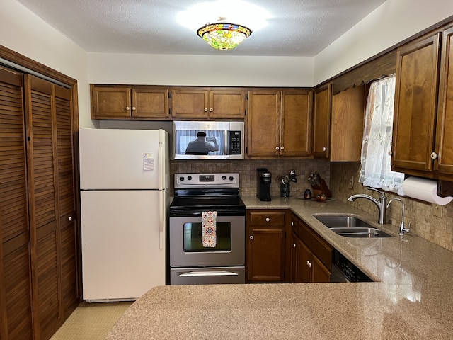 kitchen with light stone counters, decorative backsplash, a textured ceiling, sink, and appliances with stainless steel finishes