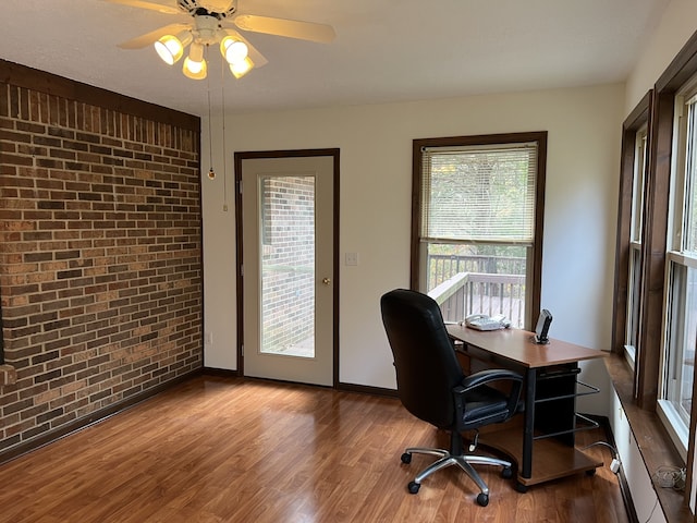 office with dark wood-type flooring, ceiling fan, and brick wall