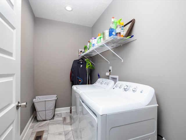 clothes washing area with a textured ceiling and washer and clothes dryer