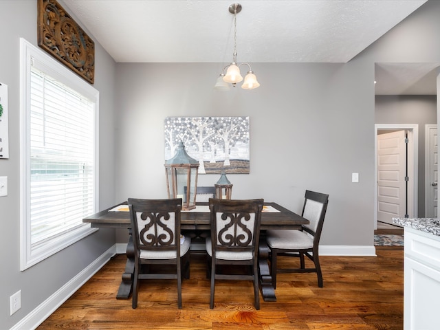 dining space featuring dark wood-type flooring and an inviting chandelier