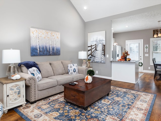 living room with a notable chandelier, dark wood-type flooring, and vaulted ceiling