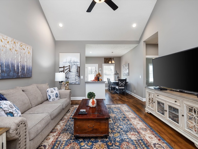 living room featuring dark hardwood / wood-style flooring, high vaulted ceiling, a wealth of natural light, and ceiling fan with notable chandelier