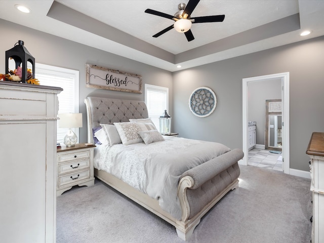 carpeted bedroom featuring ceiling fan, a tray ceiling, and connected bathroom