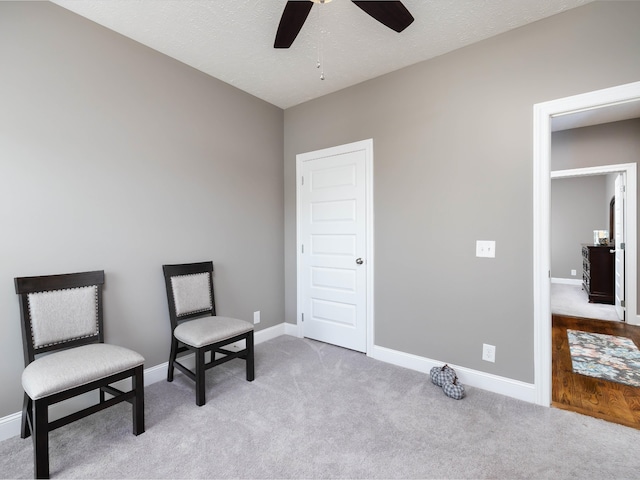 living area with light colored carpet, a textured ceiling, and ceiling fan