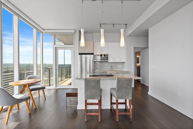 kitchen with white cabinetry, appliances with stainless steel finishes, dark hardwood / wood-style flooring, light stone countertops, and decorative backsplash