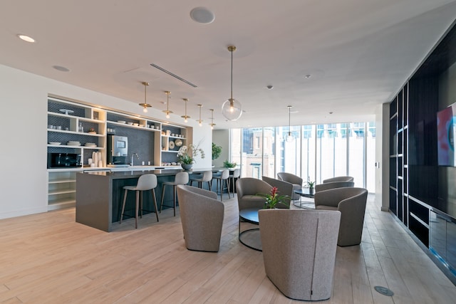 living room with a wall of windows and light hardwood / wood-style flooring