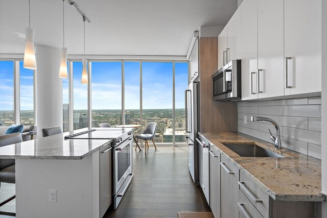 kitchen featuring stainless steel appliances, white cabinetry, sink, a kitchen bar, and hanging light fixtures