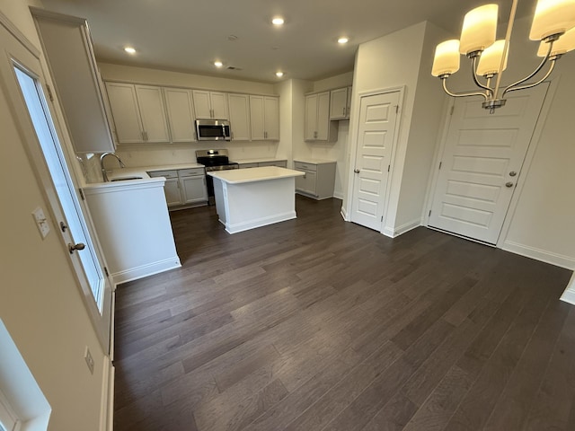 kitchen with a center island, dark hardwood / wood-style flooring, stainless steel appliances, sink, and hanging light fixtures